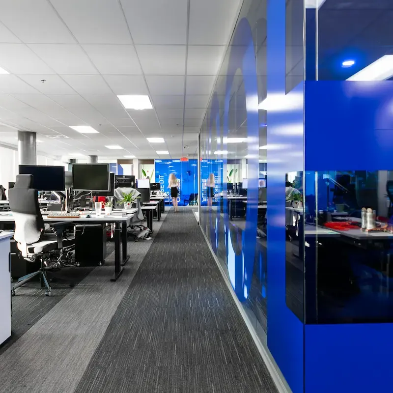 Image d'un espace de bureau professionnel avec des murs bleus et des bureaux blancs bien rangés.